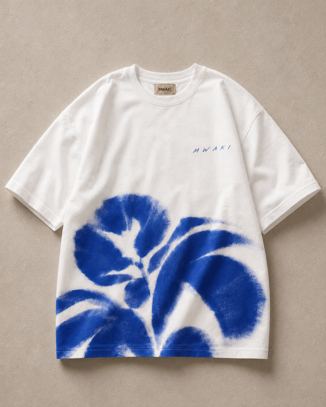 MWAKI Art Tee White on a warm stone background